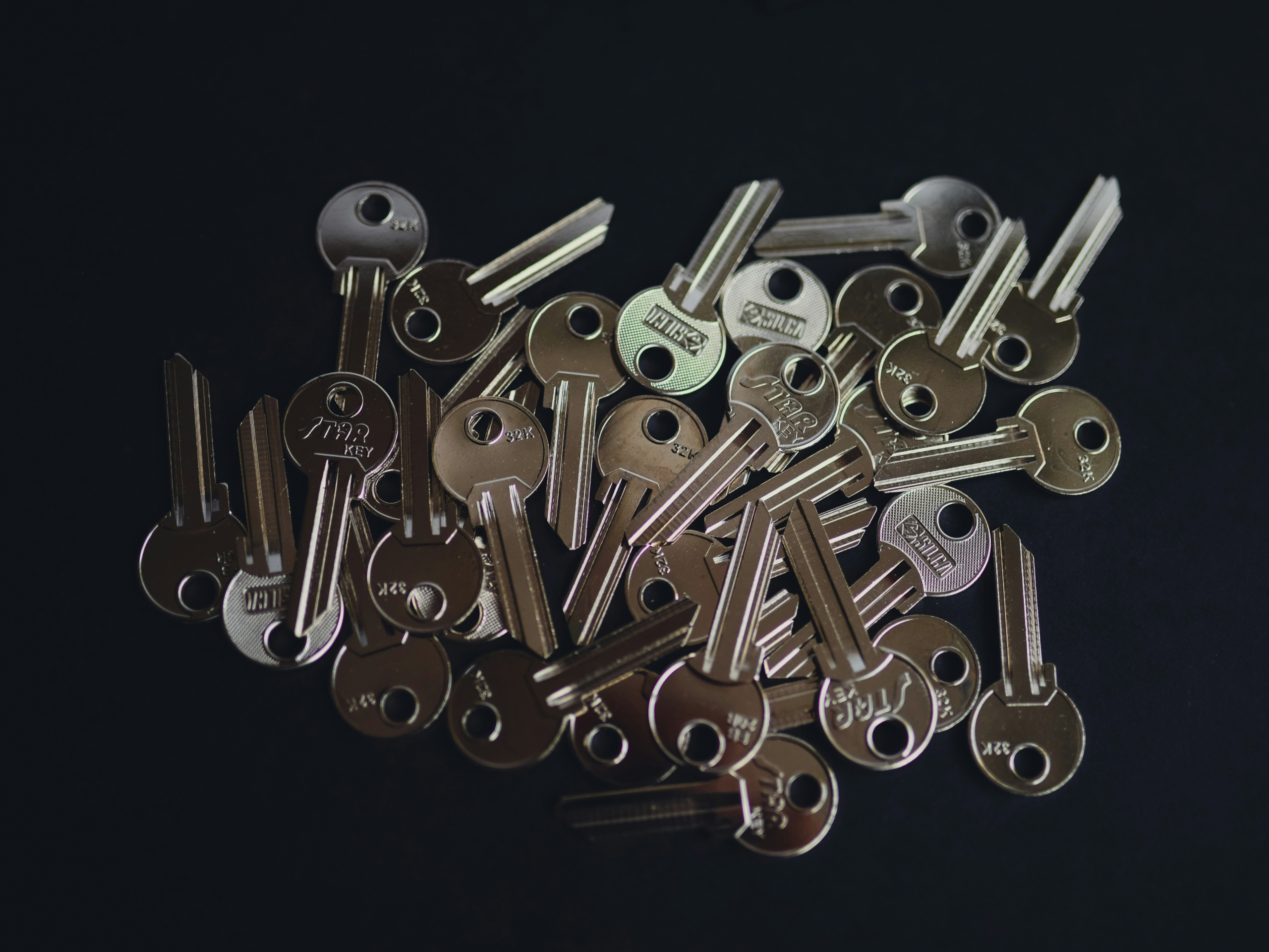 黒い背景の上に無造作に置かれた大量の金属鍵。ログイン認証が記憶から外部の鍵へ移行したことを示すイメージ。